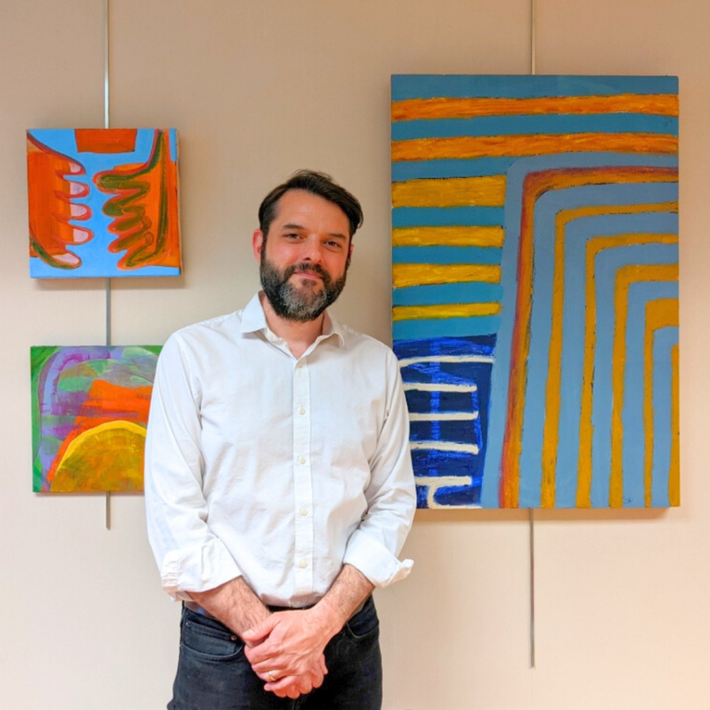 A picture of James Vanderberg with some of his paintings.